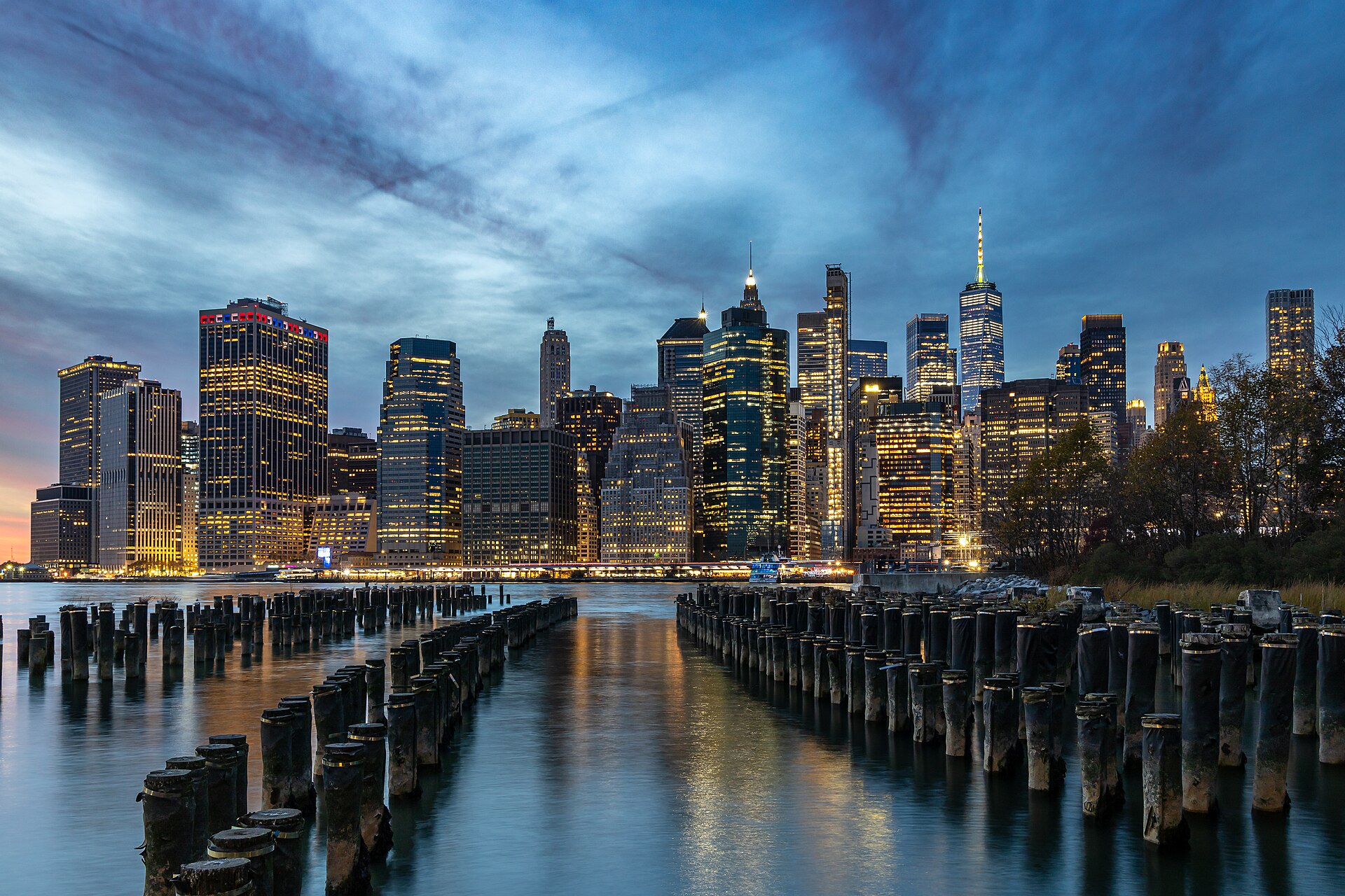 Lower Manhattan skyline illuminated at dusk, viewed across the East River
